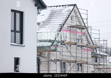 14 janvier 2021, Saxe, Klaffenbach : panneau publicitaire pour la construction de terrains devant un chantier de construction d'une nouvelle maison dans un développement enneigé. Photo: Jan Woitas/dpa-Zentralbild/ZB Banque D'Images