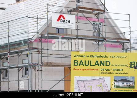 14 janvier 2021, Saxe, Klaffenbach : panneau publicitaire pour la construction de terrains devant un chantier de construction d'une nouvelle maison dans un développement enneigé. Photo: Jan Woitas/dpa-Zentralbild/ZB Banque D'Images