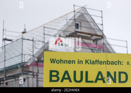 14 janvier 2021, Saxe, Klaffenbach : panneau publicitaire pour la construction de terrains devant un chantier de construction d'une nouvelle maison dans un développement enneigé. Photo: Jan Woitas/dpa-Zentralbild/ZB Banque D'Images