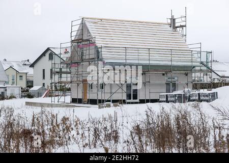 14 janvier 2021, Saxe, Klaffenbach : panneau publicitaire pour la construction de terrains devant un chantier de construction d'une nouvelle maison dans un développement enneigé. Photo: Jan Woitas/dpa-Zentralbild/ZB Banque D'Images