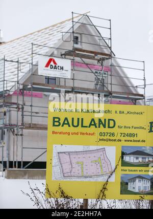 14 janvier 2021, Saxe, Klaffenbach : panneau publicitaire pour la construction de terrains devant un chantier de construction d'une nouvelle maison dans un développement enneigé. Photo: Jan Woitas/dpa-Zentralbild/ZB Banque D'Images