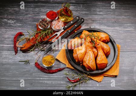 Nourriture pratique, pree cuit.pattes de poulet bio brutes avec des ingrédients pour la cuisson marinatiningon une planche à découper en bois sur ardoise sombre, pierre ou contr Banque D'Images