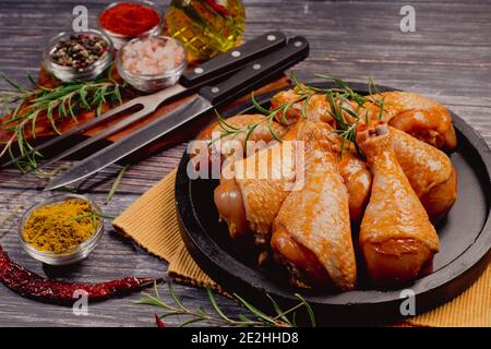 Nourriture pratique, pree cuit.pattes de poulet bio brutes avec des ingrédients pour la cuisson marinatiningon une planche à découper en bois sur ardoise sombre, pierre ou contr Banque D'Images