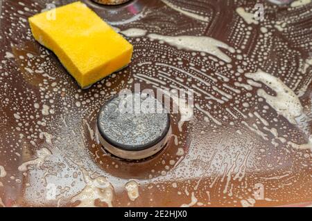 Vieille cuisinière à gaz sale avec la surface dans la cuisine des taches d'huile de cuisson et avec la mousse chimique de nettoyage qui dissolvent la saleté, les graisses. Élimination de la graisse. Banque D'Images