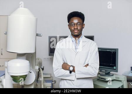 Gros plan portrait d'un beau homme africain souriant, debout devant les échographes et les lithotripteurs et montrant le pouce vers le haut. Sécurité non Banque D'Images