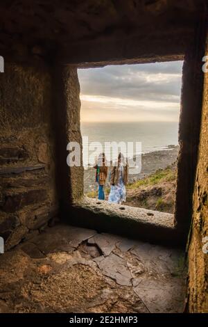 Vue sur la mer et randonneurs touristes à travers le trou de fenêtre dedans Ancienne maison en pierre abandonnée en France Banque D'Images