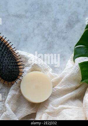 Bar à shampooing solide avec huile d'argan isolée sur un marbre planche et une brosse à cheveux Banque D'Images