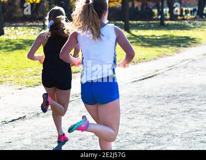 Vue arrière de deux coureurs de fond de lycée qui s'affrontent dans le tout dernier tout droit sur un chemin de gravier essayant de gagner la course. Banque D'Images