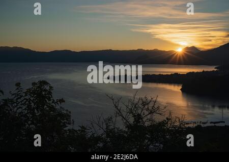 Lever du soleil sur le lac Atitlán le soleil se levant derrière les montagnes Et volcans - premiers rayons de soleil sur le beau lac À Sololá Guatemala Banque D'Images