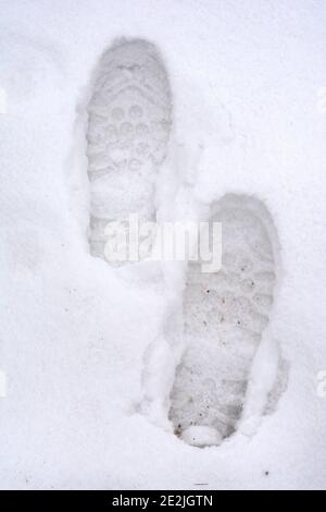 Vue en hauteur des empreintes humaines sur fond blanc de neige d'hiver. Banque D'Images
