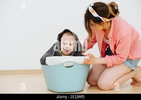 Maman joue avec son fils, il est assis dans un panier avec du linge propre Banque D'Images