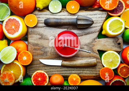 Mélanger différents agrumes et un verre de jus avec une planche en bois, un presse-fruits et un couteau. Concept de vitamine saine alimentation. Photographie alimentaire Banque D'Images