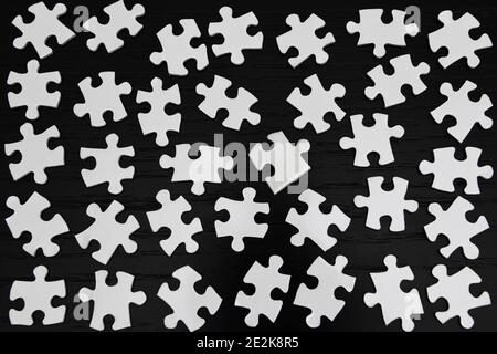 Pièces de puzzle blanches sur une table noire Banque D'Images