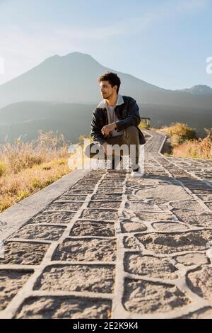 Jeune voyageur au sommet de la montagne en regardant le lever du soleil Au lac Atitlán - jeune homme hispanique qui profite du lever du soleil avec des volcans et des montagnes Banque D'Images