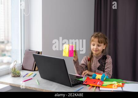 Portrait de jolie petite fille souriant joyeusement à l'appareil photo tout en faisant des décorations de Noël faites à la main pendant la classe d'art et d'artisanat d'avant-école, copie Banque D'Images