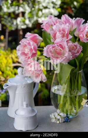 Vase avec fleurs de tulipe rose clair dans le jardin ensoleillé du printemps le matin Banque D'Images