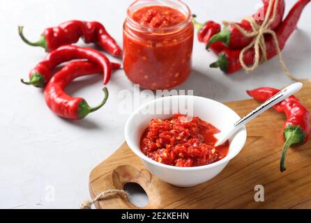 Sauce traditionnelle adjika au piment fort, collez l'harissa dans un bol sur une planche de bois. Banque D'Images