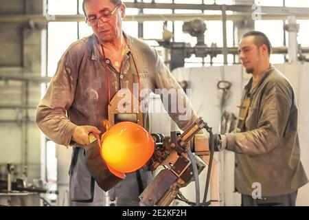 Transformer une masse chaude de verre tirée d'un four chaud en une œuvre d'art le processus de fabrication du verre de près. Maître de verre créatifs un vase dans Moser G. Banque D'Images