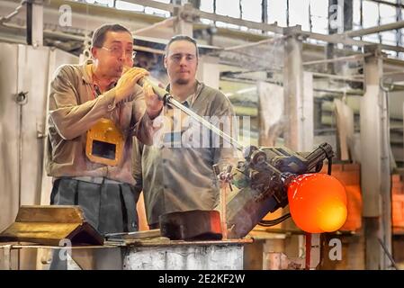 Transformer une masse chaude de verre tirée d'un four chaud en une œuvre d'art le processus de fabrication du verre de près. Maître de verre soufflant un vase dans Moser Gla Banque D'Images