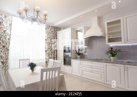 Photo de epmty intérieur minimaliste, l'arrière-plan cuisine dans appartement moderne avec grande fenêtre, rideau, table, chaises, compteur, l'équipement et des fleurs o Banque D'Images