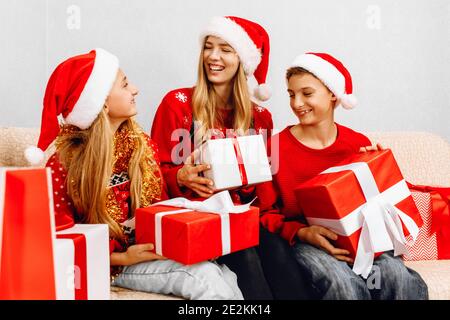 Bonne année et joyeux Noël ! Une famille heureuse, une jeune mère avec des enfants, portant des chapeaux du père noël, salue le nouvel an et se donne un autre Chr Banque D'Images