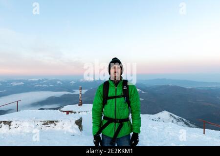 Le portrait d'un homme vêtu de matériel de montagne au sommet d'une montagne. Banque D'Images