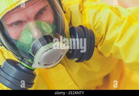 Travailleur caucasien fatigué dans ses 40 ans portant un costume de Hazmat jaune et de protection respiratoire masque complet. Zone de risque biologique. Thème industriel. Banque D'Images