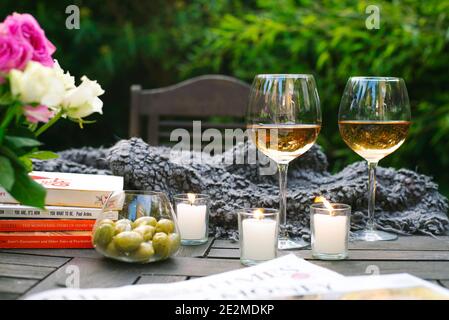 Vin, olives et livres sur une table en bois dans le jardin extérieur. Décoration chaleureuse, table décontractée. L'été, le style de vie décontracté du week-end au Royaume-Uni Banque D'Images