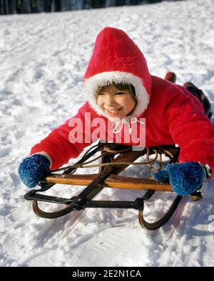 ANNÉES 1970 PETITE FILLE PORTANT UNE PARKA ROUGE CAPUCHE MOUFLES BLEUES SOURIANT DESCENTE EN TRAÎNEAU À NEIGE - KW3622 HAR001 HARS ESPACE DE COPIE MITAINES DEMI-LONGUEUR CONFIANCE HIVER BONHEUR GAI GRAND ANGLE AVENTURE DESCENTE LOISIRS EXCITATION LOISIRS PARKA SOURIRES JOYEUSE CROISSANCE HIVERNANTE JUVÉNILES ORIGINE CAUCASIENNE HAR001 ANCIEN MODE Banque D'Images