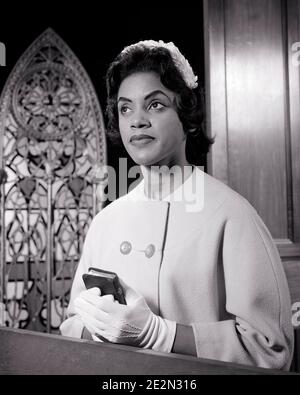 ANNÉES 1960 FEMME AFRO-AMÉRICAINE DANS L'ÉGLISE PEW PORTANT CHAPEAU BLANC ET GANTS TENANT UN PETIT LIVRE DE PRIÈRE BIBLIQUE - N1005 HAR001 HARS B&W RELIGIEUX AFRO-AMÉRICAINS AFRO-AMÉRICAINS ET LE CHRISTIANISME PRIENT RÉFLEXION L'ETHNIE NOIRE REFLÉTANT LA RÉFLEXION DES MÉDITER CONSIDÈRE PERDU DANS LA PENSÉE ÉLÉGANTE CONTEMPLATIVE FIDÈLE MÉDITER LA FOI MÉDITATIVE MOYENNE-ADULTE MOYENNE-ADULTE FEMME PEW SPIRITUELLE CROYANCE NOIR ET BLANC CONSIDÉRANT LE DÉVOT HAR001 INSPIRÉ VIEUX MODE AFRO-AMÉRICAINS Banque D'Images