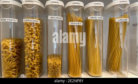 Une étagère de garde-manger organisée avec divers types de pâtes dans des récipients en plastique. Banque D'Images