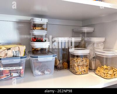 Une étagère de garde-manger organisée avec divers types de biscuits, céréales et en-cas mis tidlily dans des récipients en plastique. Banque D'Images