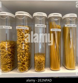 Une étagère de garde-manger organisée avec divers types de pâtes dans des récipients en plastique. Banque D'Images