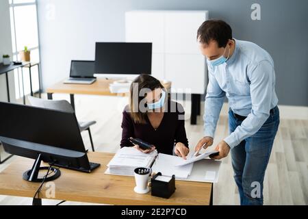 Formation de l'assistant employé portant un masque facial au bureau Banque D'Images