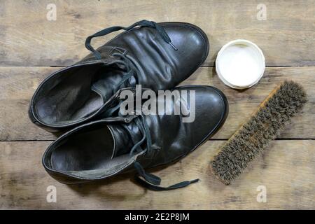 vieilles chaussures en cuir avec cirage de chaussures et brosses contre les personnes âgées panneaux en bois fissurés Banque D'Images