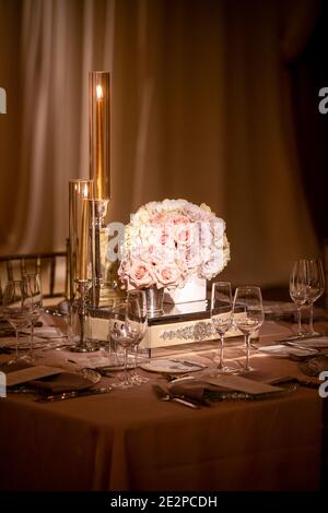 Table de mariage pour une cérémonie du soir dans un thème doré avec de grandes bougies, et un beau bouquet de roses Banque D'Images