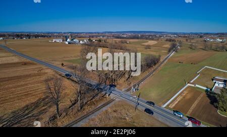 Vue aérienne des fermes et des champs Pulse a Rail Road Suivez en hiver sur un ciel sans nuages Banque D'Images