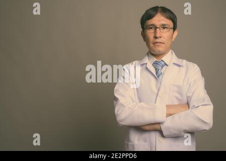 Jeune homme asiatique médecin portant des lunettes sur fond gris Banque D'Images