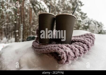 Deux tasses en papier avec café gardent au chaud sur un foulard dans la neige, conte d'amour d'hiver Banque D'Images