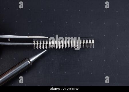 Outils de soudage. Fer à souder, brucelles et micropuce, sur fond noir Banque D'Images