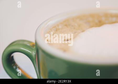 Café dans une tasse en céramique verte Cappuccino avec mousse, tasse Latte Capuccino en gros plan. Latte au café chaud dans une tasse en porcelaine de couleur jade Banque D'Images