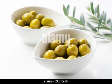 Olives salées et branches d'olive placées sur un fond blanc Banque D'Images