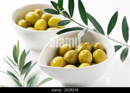 Olives salées et branches d'olive placées sur un fond blanc Banque D'Images