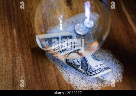 Une grosse bulle sur un billet de dollar et deux pièces qui sont entourées de mousse. Banque D'Images