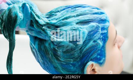 Le coiffeur professionnel tient les longs cheveux bleus du client en main tout en se lavant les cheveux après le processus de teinture des cheveux dans la belle couleur bleu foncé. Banque D'Images