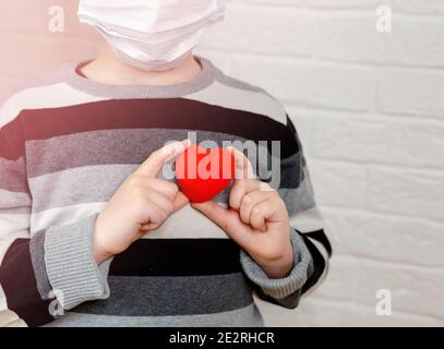 Enfant triste et désespéré tenant le cœur rouge jouet dedans mains Banque D'Images