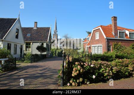 Broek à Waterland, petite ville avec maisons traditionnelles en bois anciennes et peintes, Hollande du Nord, pays-Bas, avec le clocher de l'église Banque D'Images