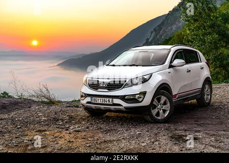 Kia Sportage 2.0 CRDI awd ou 4x4, blanc, garé sur route de montagne, avec beau lever de soleil orange en arrière-plan. Point de vue Kozja stena, Banque D'Images