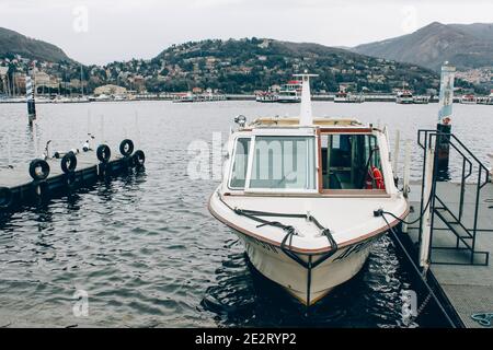 Como, région Lombardie, Italie - 14 janvier 2021 : petit bateau dans le port du lac de Côme, quai du ferry dans la sombre journée d'hiver. Location de bateau pour les touristes et Banque D'Images