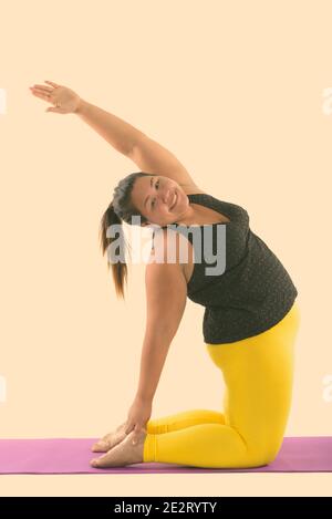 Studio shot of young woman smiling Asian fat heureux tout en faisant du yoga pose Banque D'Images